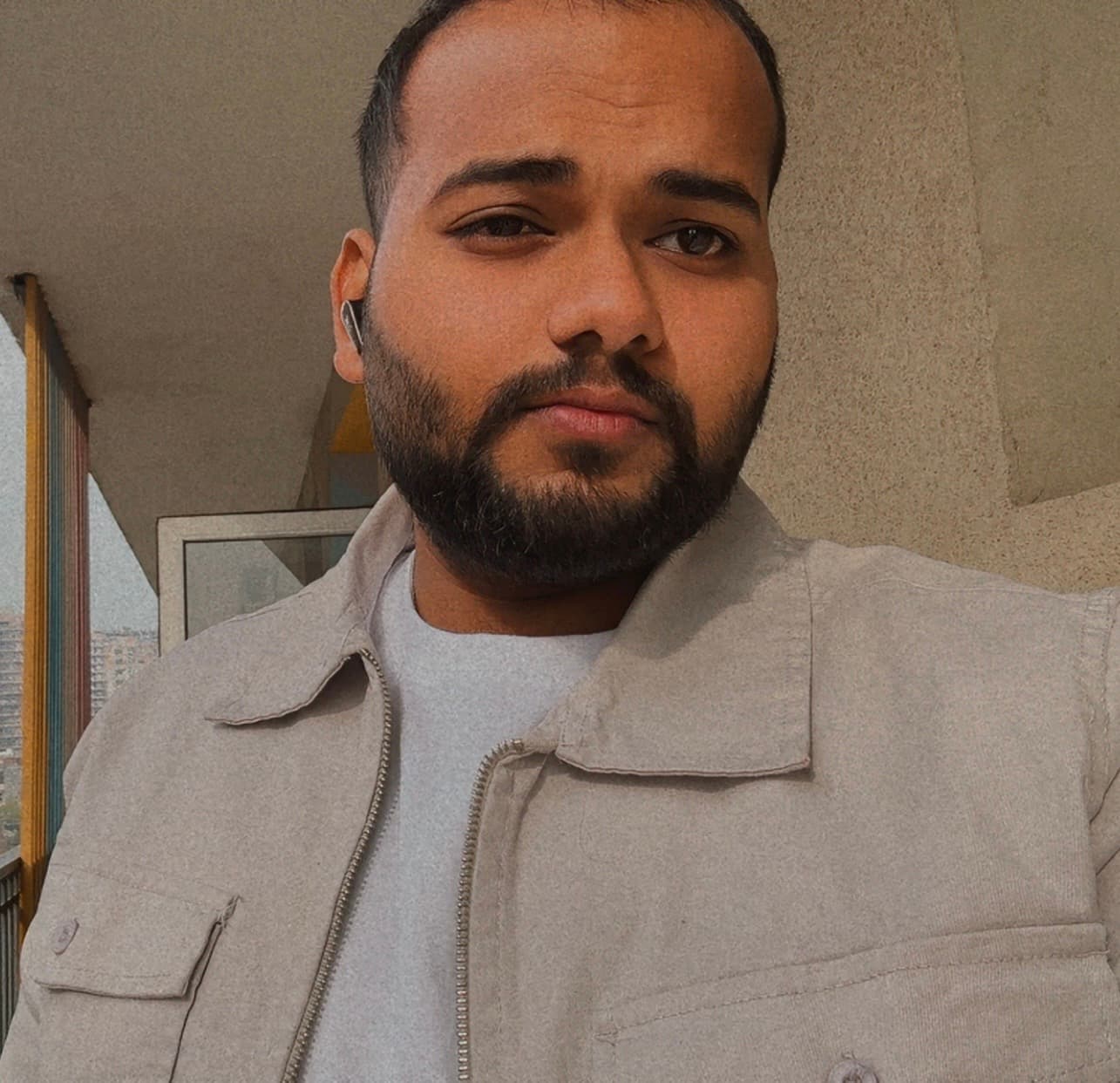 Portrait of Sushil Kumar smiling in a yellow bomber jacket on a beige background